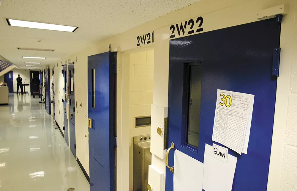 A corrections officer stands at the end of the "suicide watch" cell corridor at the Spokane County Jail. - JACOB JONES