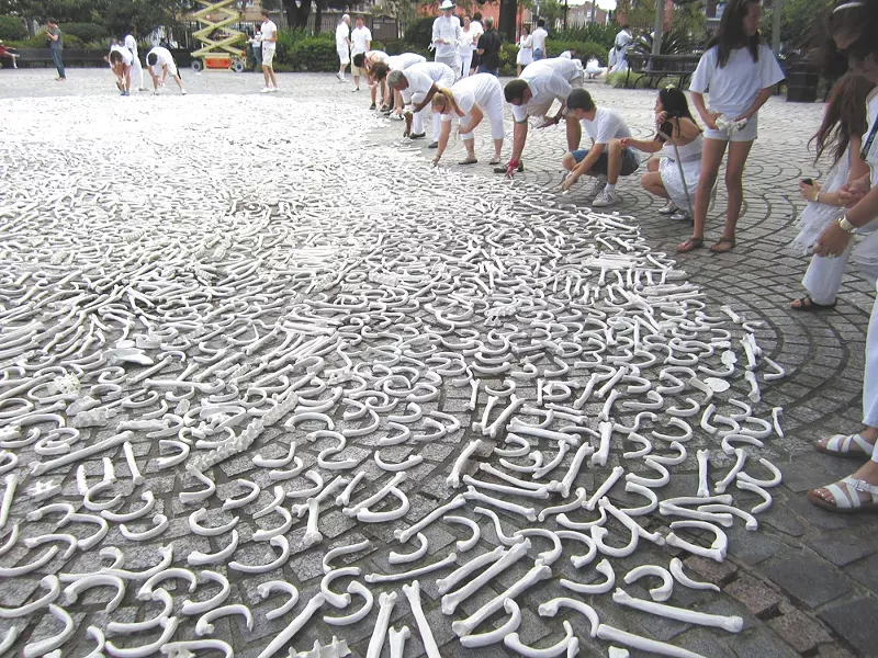 Artists arrange thousands of “bones,” a symbol of those killed in international conflicts.