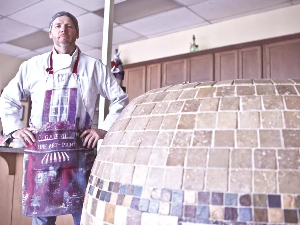 Asian Cafe owner Andrey Chumov stands beside the tandoor oven in which he makes meat-filled pastries or samsas. - JORDAN BEAUCHAMP