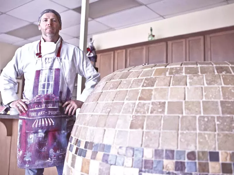 Asian Cafe owner Andrey Chumov stands beside the tandoor oven in which he makes meat-filled pastries or samsas. - JORDAN BEAUCHAMP