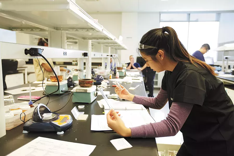 At the compounding lab, students practice custom-crafting medications. Here, Hien Tran considers which vessel to use. - YOUNG KWAK