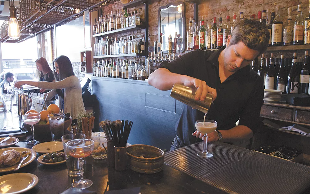 Bartender Graham Lilly strains a mixed drink into a cocktail glass at the Black Cypress Bar & Kitchen on a busy Thursday evening. - JACOB JONES
