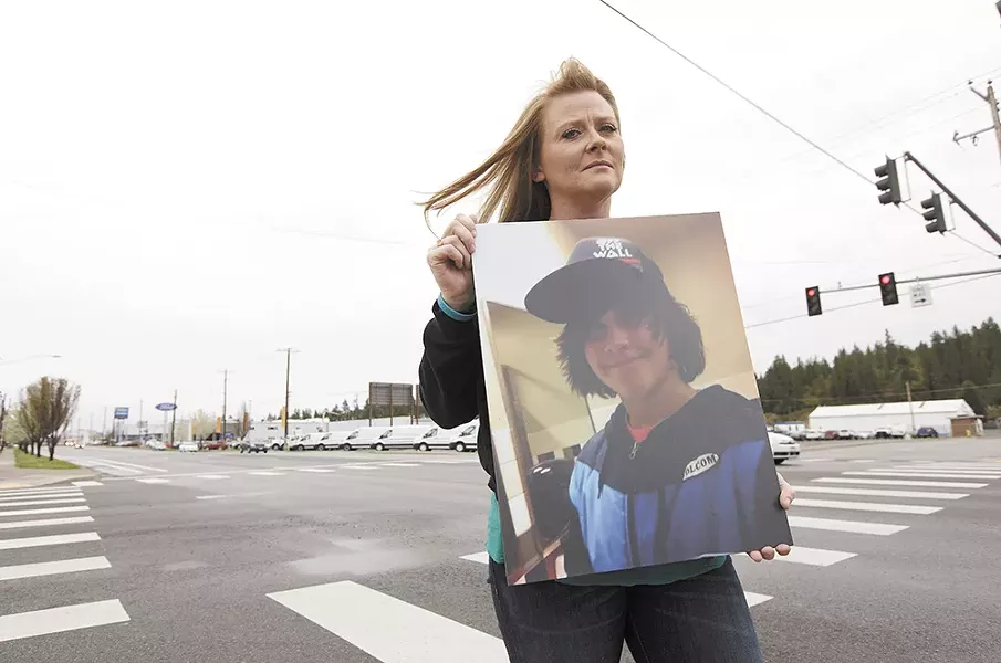 Carrie Thomson holding a photograph of her son Ryan Holyk at the intersection where Ryan sustained fatal injuries. - YOUNG KWAK