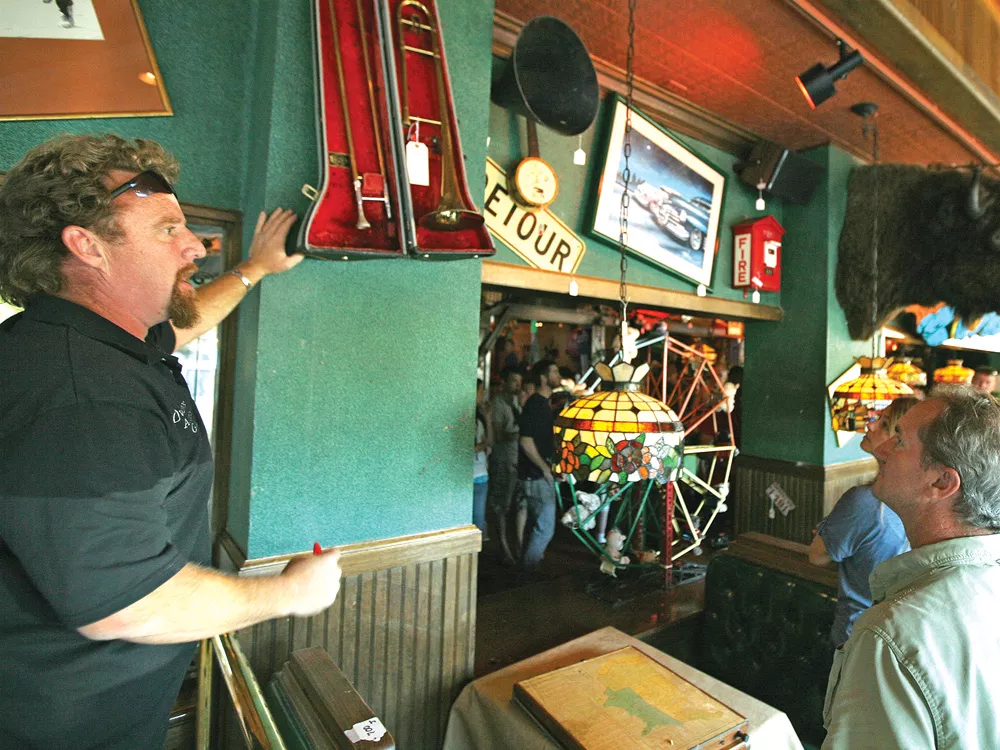 Chet Culp of Owen’s Auction helps sell one of 150 pieces of decor on the walls at now-shuttered Cyrus O’Leary’s. - YOUNG KWAK