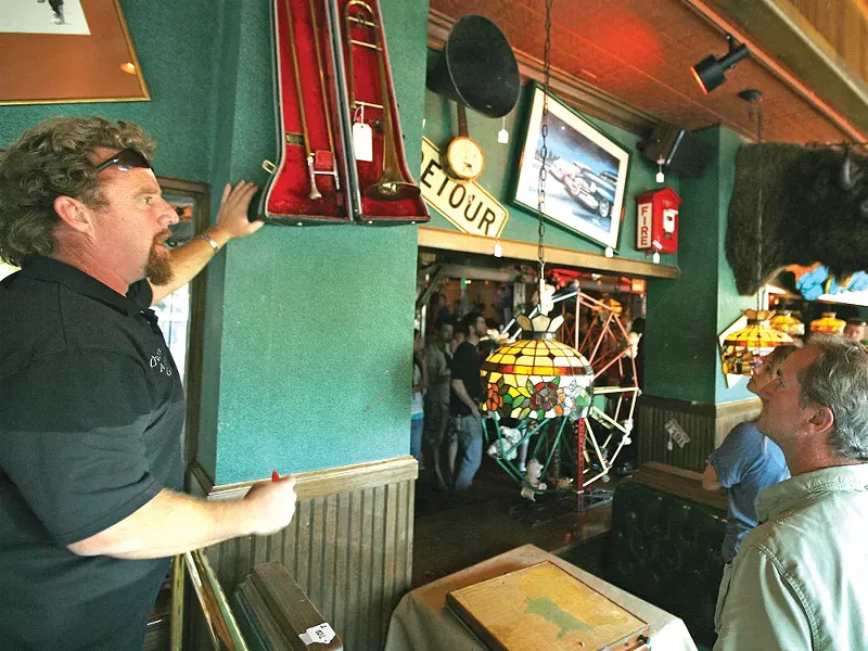 Chet Culp of Owen’s Auction helps sell one of 150 pieces of decor on the walls at now-shuttered Cyrus O’Leary’s. - YOUNG KWAK