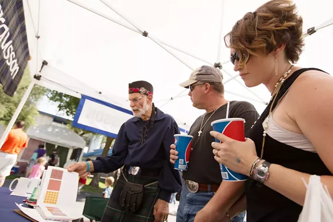 Dan Ferguson, left, shows a book of tartans to Dan, center, and Laci Murdock at the Clan Fergusson tent. Dan Murdock was looking for his family's tartan. - YOUNG KWAK