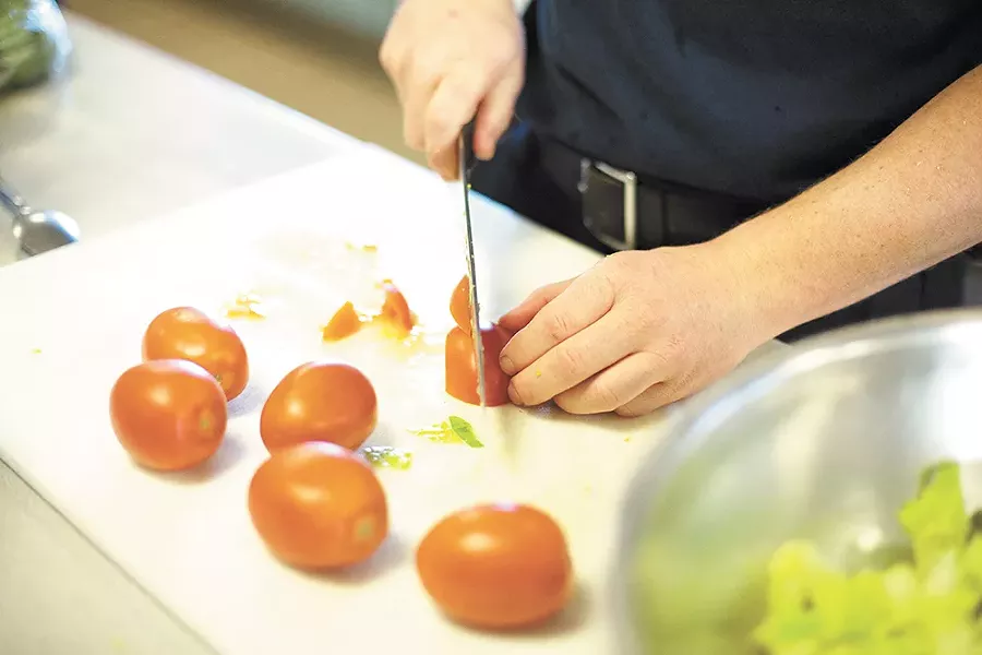 Firefighter Jason Keen slices a tomato for a salad.| - YOUNG KWAK