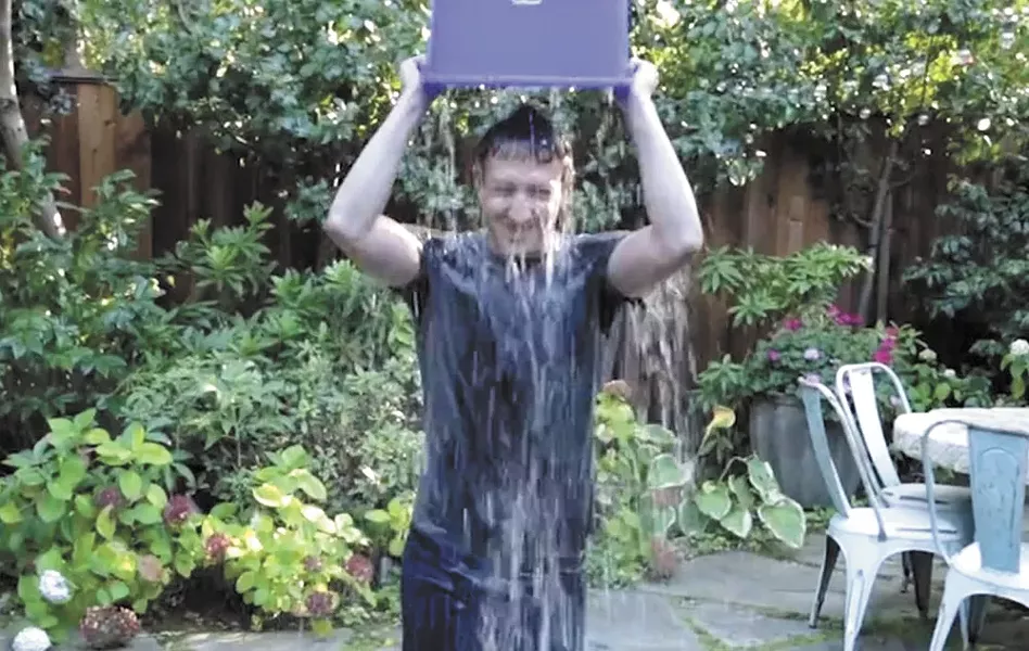 Millennial Mark Zuckerberg, 30-year-old creator of Facebook, dumps freezing water on his head for the Ice Bucket Challenge.