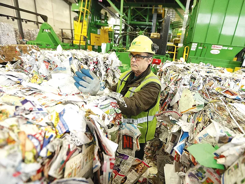 Rick McHenry removes items that don\'t belong from a bale of paper at Waste Management\'s SMaRT Center. - YOUNG KWAK