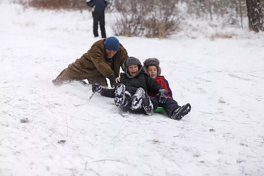 Ron Jones, left, pushes his grandsons, 6-year-old Desean Dunbar, center, and 7-year-old Zavion Lofton, down the slope at Underhill Park. - YOUNG KWAK