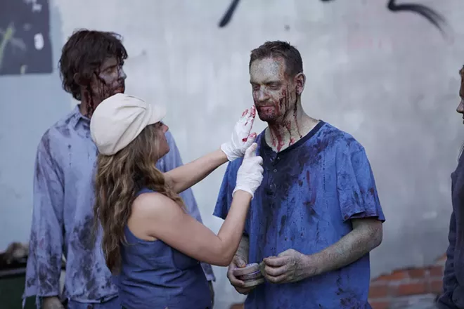 Special Effects and Makeup Artist Heather Dupree, center, touches up makeup on zombie extra Josh Depue, right, as James Gallina looks on. - GAL