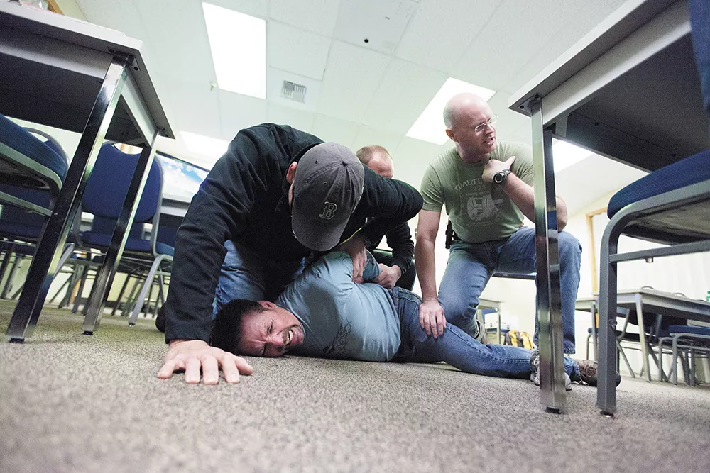 Spokane Police Officers Maurio Jaurez, left, Brad Moon, center, and Greg Ronan, right, subdue fellow Officer Ron Tilley, playing the role of a psychotic subject with excited delirium during Crisis Intervention Training. - YOUNG KWAK