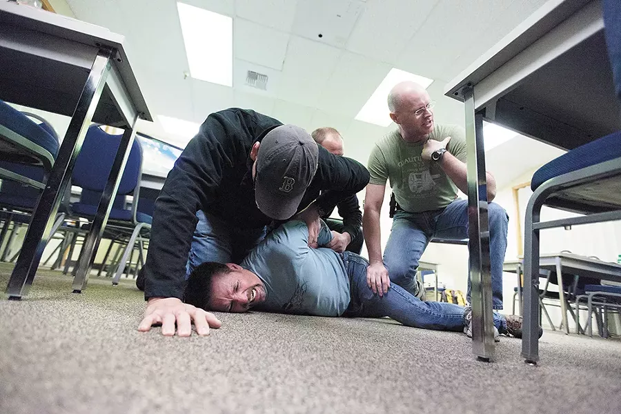 Spokane Police Officers Maurio Jaurez, left, Brad Moon, center, and Greg Ronan, right, subdue fellow Officer Ron Tilley, playing the role of a psychotic subject with excited delirium during Crisis Intervention Training. - YOUNG KWAK