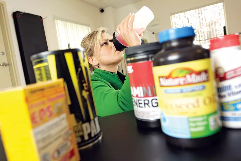 Tracy Carter, owner of Flex Ability Fitness in Spokane Valley, downs some Amino Energy before and during workouts. - YOUNG KWAK