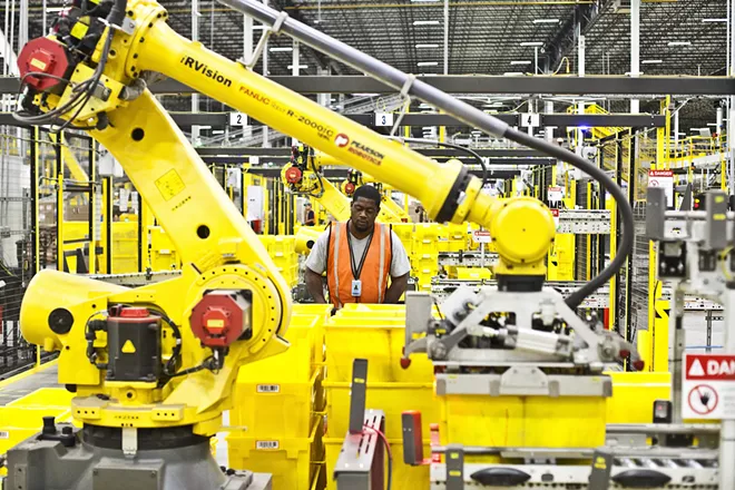An Amazon employee works alongside a robot at the company’s facility in Florence, N.J., on Aug. 29, 2017. In a move that could win favor in Washington but cut into profits, Amazon will raise the minimum wage for all of its employees in the United States to $15 an hour, it announced on Oct. 2, 2018. - (BRYAN ANSELM/THE NEW YORK TIMES)