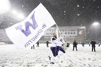 Washington punter Joel Whitford and long snapper A.J. Carty carry the school flag after their team defeated Washington State 28-15 on Nov. 23. - YOUNG KWAK