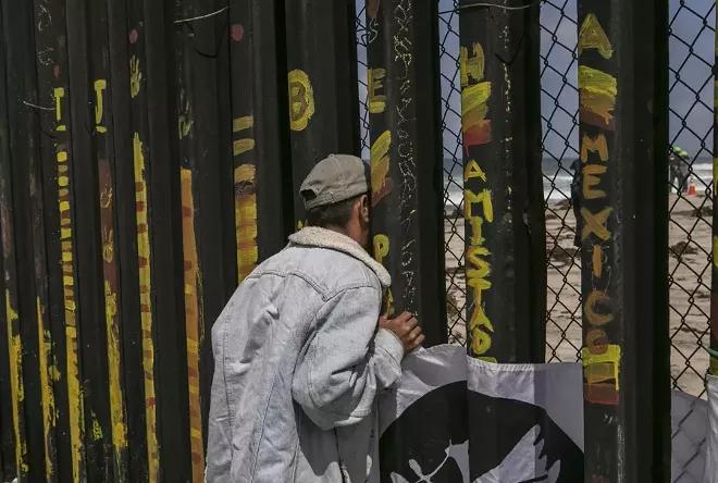 A man looks through the border wall to the US side, in Tijuana, Mexico, April 29, 2018. With a partial government shutdown stretching past Day 5, the impasse over funding a wall at the southwestern border has highlighted the debate over effective border security, with a breakthrough possibly hinging on a semantic argument: What is a wall? - MEGHAN DHALIWAL/THE NEW YORK TIMES