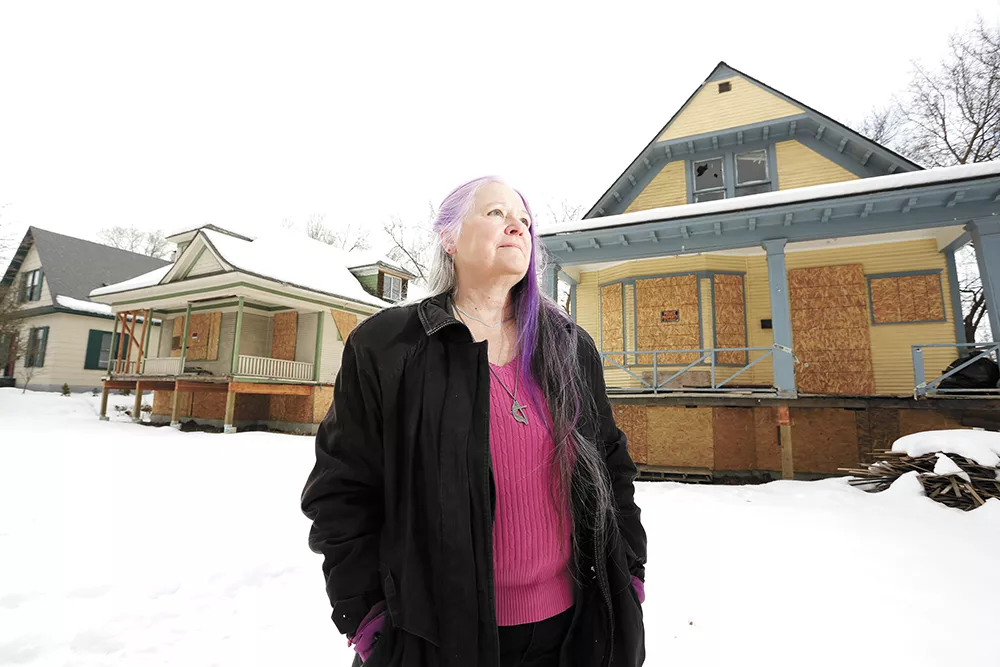 Deb Conklin stands in front of boarded-up homes she hopes to convert into affordable housing. - YOUNG KWAK PHOTO