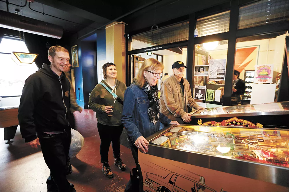 Debbie Tansy plays the Taxi pinball machine as her husband, Ray Tansy, right, David Strom, left, and Kacie Strom look on at Berserk.|young kwak photo - YOUNG KWAK PHOTO