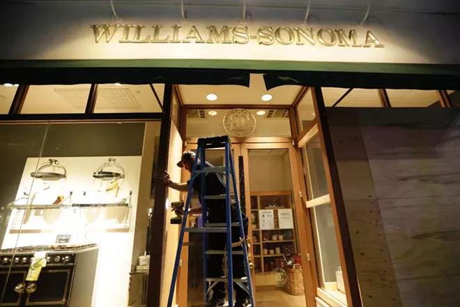 A worker boards up windows at the downtown Williams-Sonoma, hoping to deter vandals. - YOUNG KWAK PHOTO