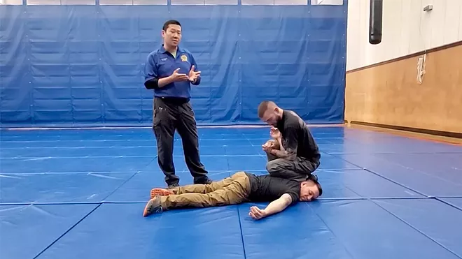 A Washington State Criminal Justice Training Commission trainer shows a “ground control knee placement drill” where an officer would place their knee on the suspect’s shoulder and another on the ground to gain control.