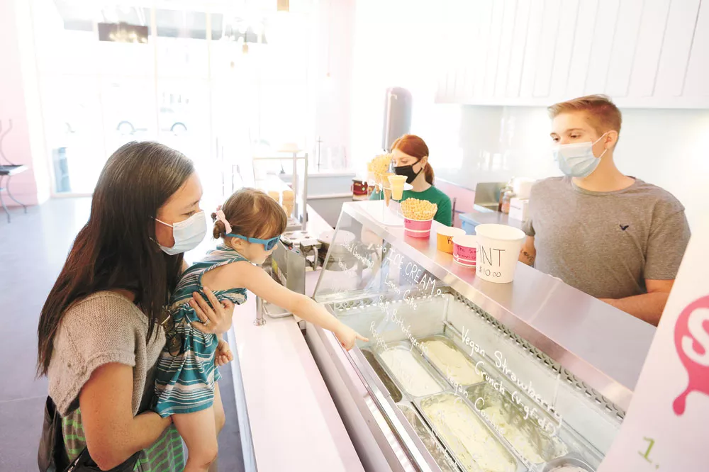 Vanessa Thomsen (left) holds her 3-year-old daughter Mariko as she orders ice cream from Marlin Jones at the Scoop in Kendall Yards. - YOUNG KWAK PHOTO