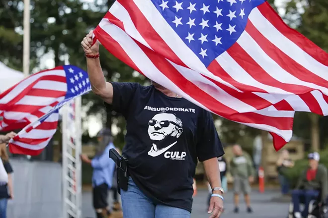 Cindy Sandland of Seattle waves a flag during a free rally and concert for Republican gubernatorial candidate Loren Culp in Arlington, Washington, on Aug. 22, 2020. - JASON REDMOND FOR CROSSCUT