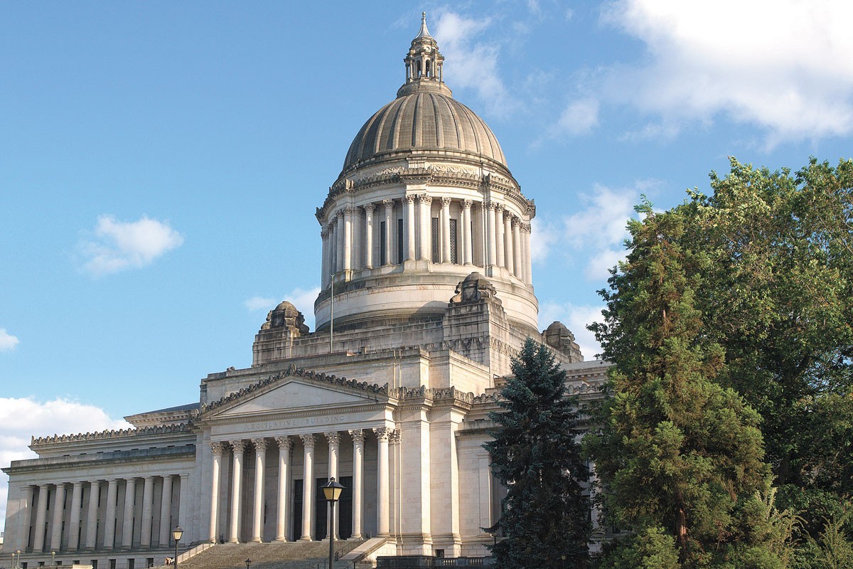 A light gray domed building with large steps and pillars stands out against a sunny blue sky. 