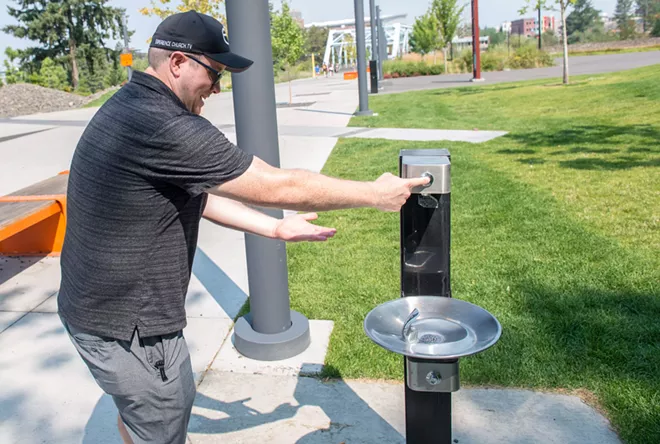 Out-of-town visitor Sam Warren showcases the inoperability of one of Riverfront Park's relatively new water fountains on Friday morning. - DANIEL WALTERS PHOTO