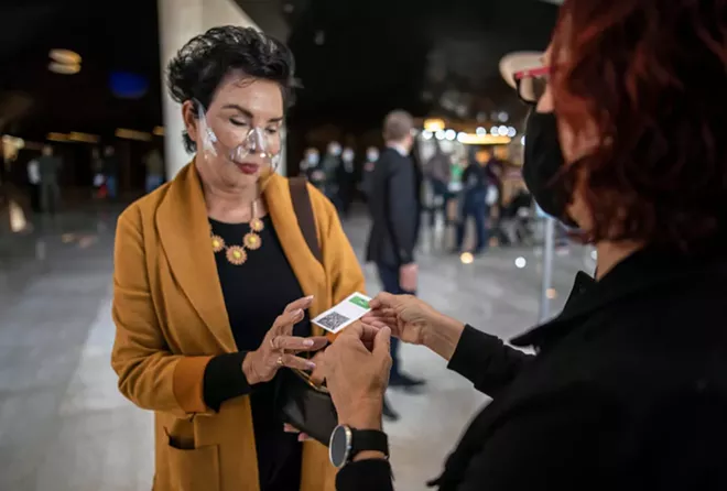 A woman shows her green passport, issued to fully vaccinated Israelis, before entering a show at the opera house in Tel Aviv, Israel, March 19, 2021. Israel on Sunday, Oct. 3, introduced new rules for determining coronavirus vaccination status, making a booster shot a requirement for full inoculation and vaccination passports. - DAN BALILTY/THE NEW YORK TIMES