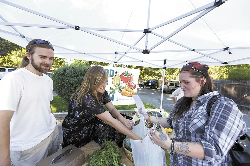 Food For All farm manager Whitney Jacques (center) and volunteer John Jozwiak (left) sell produce at the Emerson Garfield farmers market. - YOUNG KWAK