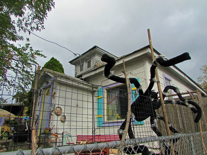 A sculpture of a spider climbs up the fence in front a Bridge Avenue lawn stuffed with quirky artwork. - DANIEL WALTERS PHOTO