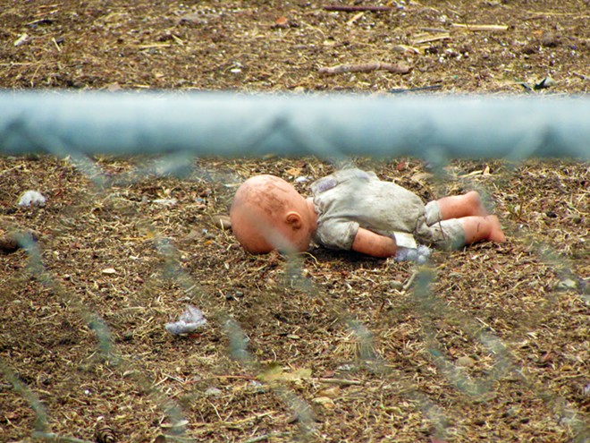 A doll lays facedown in the dirt, scattered among other toys on a lawn on Bridge. - DANIEL WALTERS PHOTO