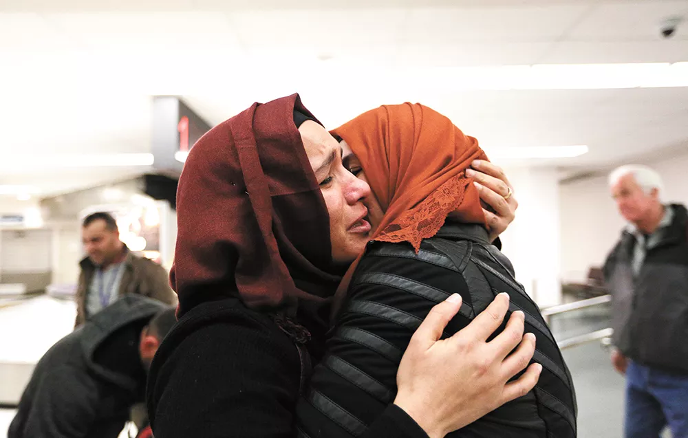 After nearly two years apart, Nadia Amzuabidi (left) hugs her sister, Iraqi refugee Athraa Jameel, tightly as they reunite at the Spokane International Airport Saturday. - YOUNG KWAK