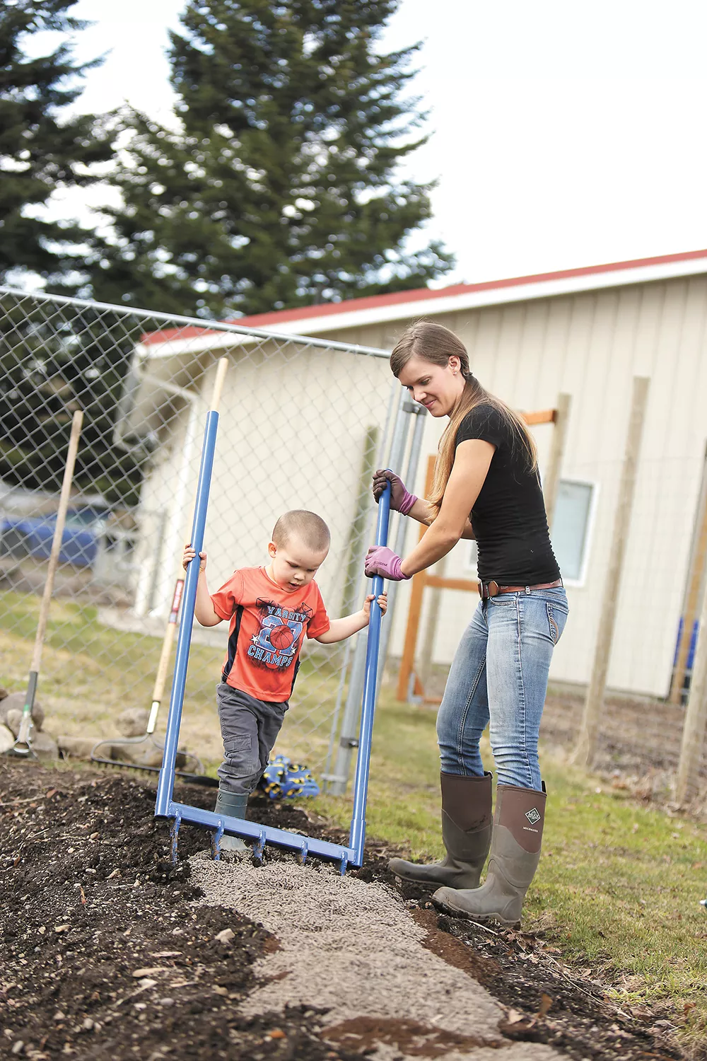 With help from her son, Idaho farmer Erica Gregerson adds organic fertilizer and chicken manure into a garden bed using a broadfork. - YOUNG KWAK