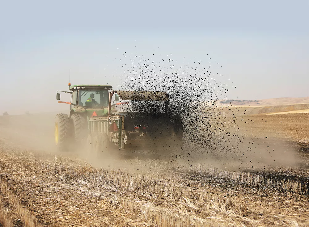 Kevin Johnbrow, from Spokane's wastewater treatment plant, spreads biosolids on a farm near Reardan last week. - YOUNG KWAK