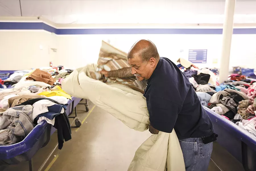 Randy Mora folds a blanket he wants to buy at the Goodwill Outlet Store. - YOUNG KWAK