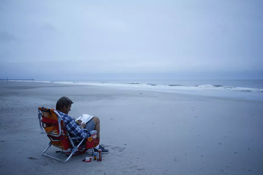 Jerry Bryant spends time on the beach before the arrival of Hurricane Florence in Myrtle Beach, S.C., Sept. 13, 2018. The first rains of Florence were starting to lash North Carolina on Thursday, with the storm growing in size, packing winds of up to 110 miles an hour and driving a storm surge that could reach 13 feet in places. - LUKE SHARRETT/THE NEW YORK TIMES