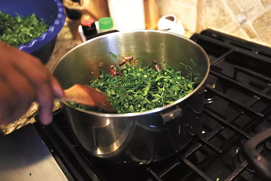 Jane Kamuasi stirs sukuma wiki, braised collard greens. - YOUNG KWAK
