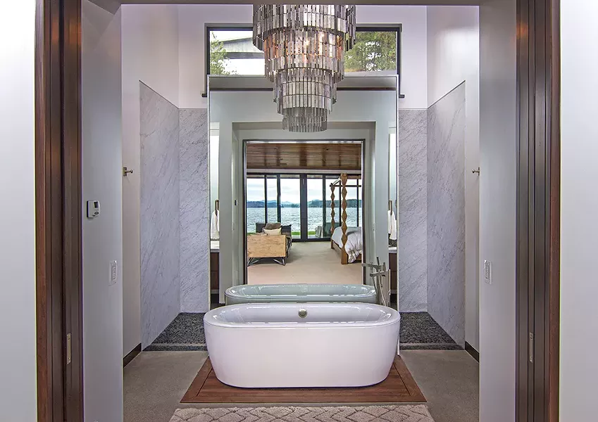 A mirror behind the bathtub, which sits on a "raft" of teak flooring, brings lake views into focus from any direction. - JOEL RINER PHOTO