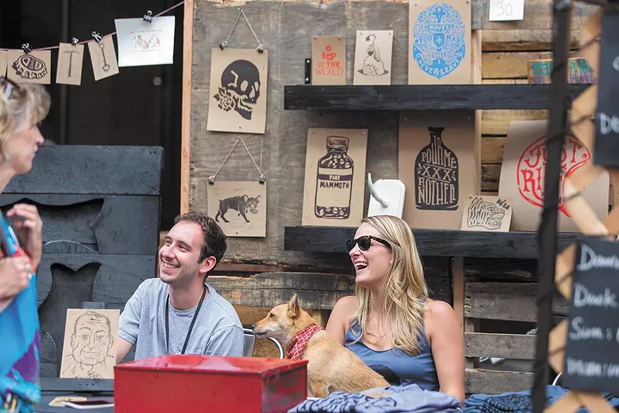 Aaron Abolofia of Tiny Mammoth Ink, left, sits with friend Melissa Estma and dog Lola at 2014's Bazaar, which resulted in about $36,000 in art sales. - MATT WEIGAND