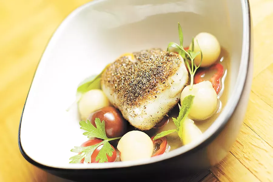 A spice-encrusted piece of halibut in a mushroom sauce, with potatoes and fresh herbs. - YOUNG KWAK