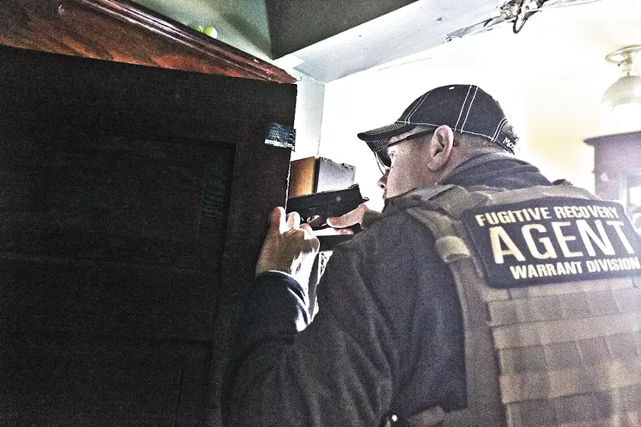 Scott Gribble draws his gun while searching a house for a fugitive. Last year Gribble made more than $100,000 chasing wanted men. - YOUNG KWAK