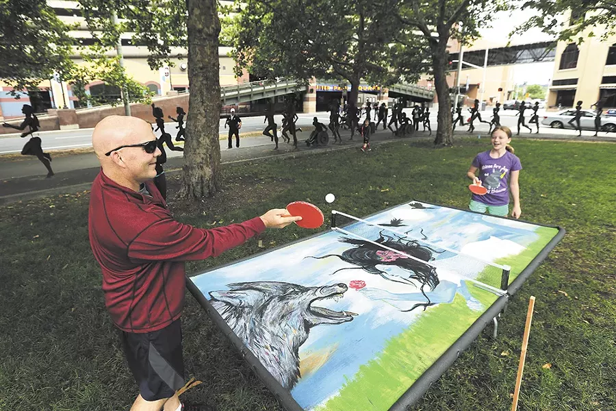 Jeff Moore and his 11-year-old daughter Shelby play ping pong on a mural by Susan Webber at Riverfront Park during a July groundbreaking event for the park’s renovation. - YOUNG KWAK