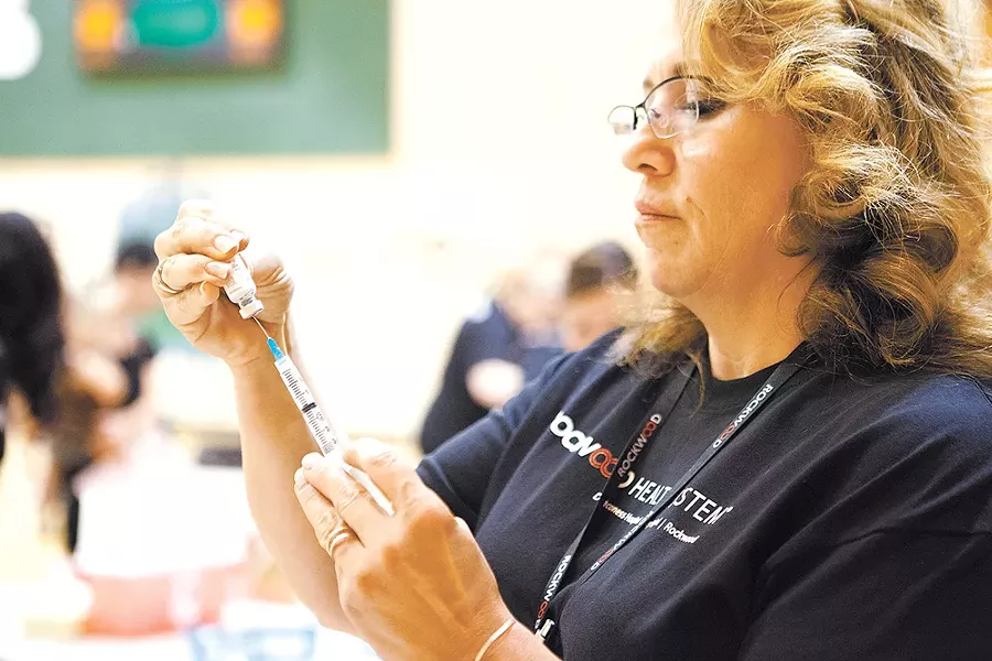 LaDon Gill, a health care worker, fills a syringe at the Greenacres Middle School immunization clinic. - KRISTEN BLACK