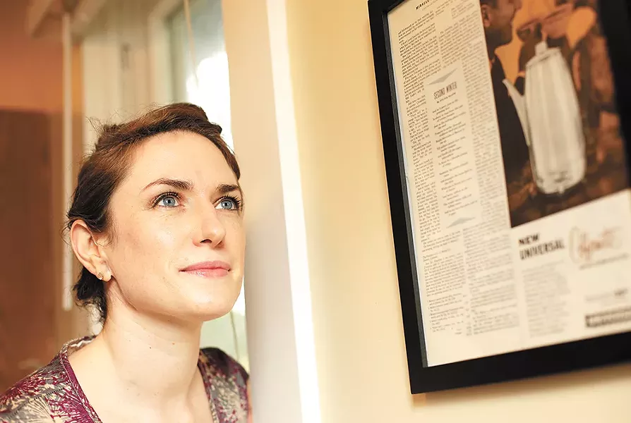Kate Lebo next to a framed poem by Sylvia Plath from Ladies' Home Journal.