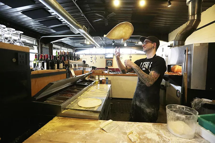 South Perry Pizza cook Nate Coyne rounds dough by tossing it into the air. - YOUNG KWAK