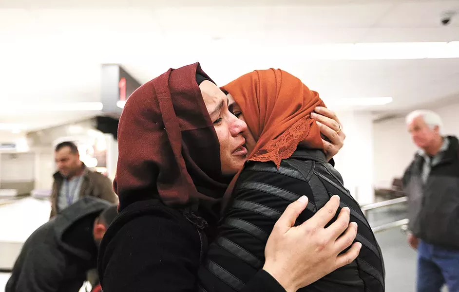 After nearly two years apart, Nadia Amzuabidi (left) hugs her sister, Iraqi refugee Athraa Jameel, tightly as they reunite at the Spokane International Airport Saturday. - YOUNG KWAK