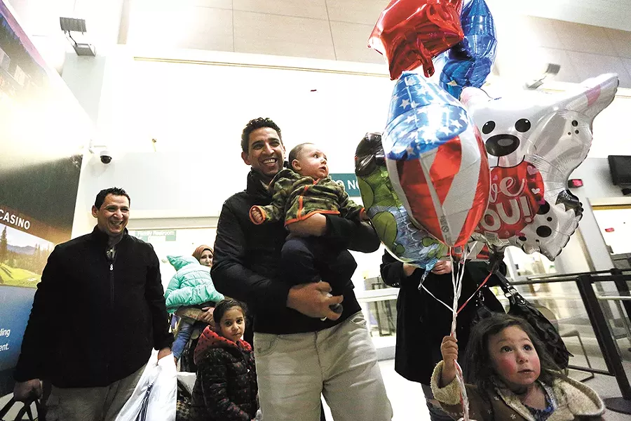 Hamid Nahi (left) smiles as his brother, Assad Al-Sawaedi, holds Nahi's son at Spokane International Airport. - YOUNG KWAK