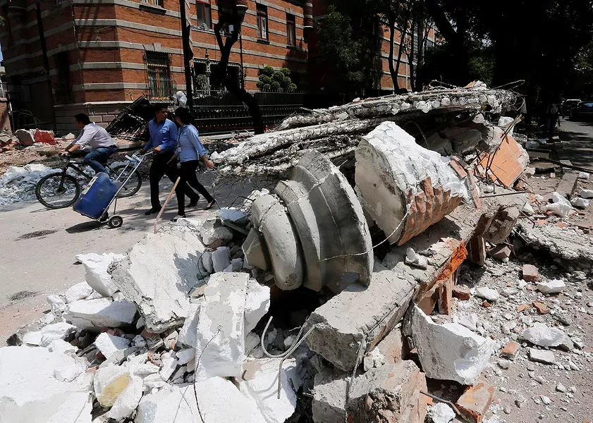 People walk next to debris after an earthquake in Mexico City on Tuesday.